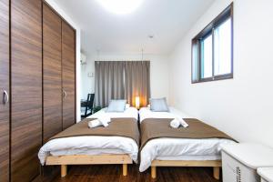 2 camas individuais num quarto com paredes brancas em Apartment Heights HANA em Sakai