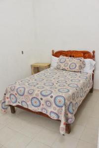 a bed with a colorful blanket and pillows on it at Hotel Posada Sernichari in Cuetzalán del Progreso