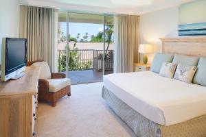 
a hotel room with two beds and a television at Aston at The Whaler on Kaanapali Beach in Lahaina
