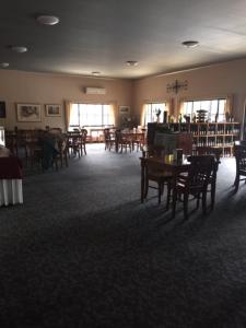 a dining room with tables and chairs and a library at Hill End Lodge in Hill End