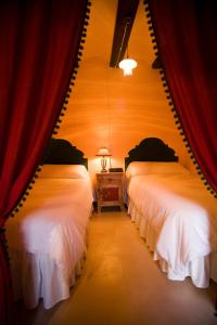 two beds in a room with a red curtain at Marques de Valdeolivo in Tronchón