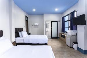 ein Hotelzimmer mit zwei Betten und einem Flachbildfernseher in der Unterkunft Udomsuk Hotel in Satun