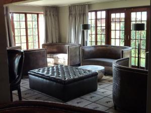 a living room with leather furniture and windows at The Highlander Hotel Dullstroom in Dullstroom