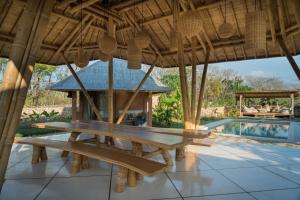 a picnic table under a roof next to a swimming pool at Maringi Sumba by Sumba Hospitality Foundation in Waikelo