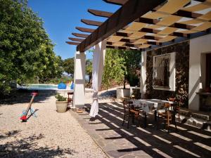 un patio con mesa y sillas bajo una pérgola en Villa Maria, en Dorgali