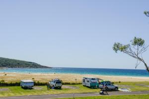a group of vehicles parked next to a beach at Ingenia Holidays Merry Beach in Kioloa