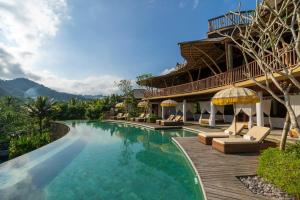 a resort with a swimming pool with chairs and umbrellas at Wapa di Ume Sidemen in Sidemen