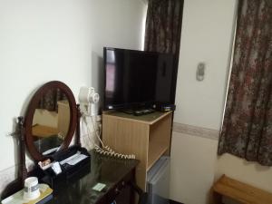 a room with a television on a dresser with a mirror at 鑽石大旅社 in Pingtung City
