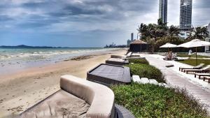 a row of benches on a beach next to the ocean at VERANDA PATTAYA BY LUX - Beach Collection in Jomtien Beach