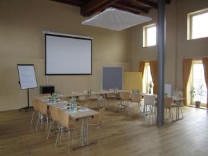 una sala de conferencias con mesas, sillas y una pantalla en JUFA Hotel Weinviertel - Eselsmühle, en Seefeld