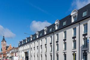 a white building with a black roof on a street at Best Western Le Beffroi in Loos