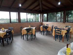 una sala da pranzo con tavoli, sedie e finestre di Agriturismo Quattro Mori a Porto Torres