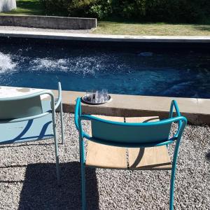 duas cadeiras azuis sentadas ao lado de uma mesa e água em Moulin Renaudiots - Maison d'hôtes em Autun
