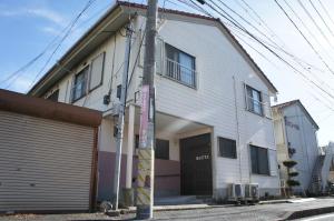 a large white building with a garage at Guest House MEETS Okayama 全室個室のホステル in Okayama