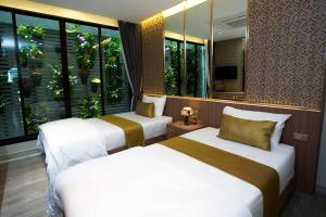 two beds in a hotel room with windows at GHEE GELATO HOUSE in Bangkok