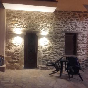 Habitación con pared de piedra, silla y luces. en To petrino holidays house en Metangítsion