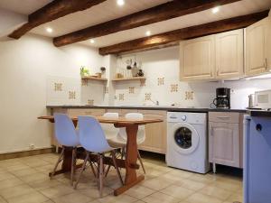 een keuken met een tafel en een wasmachine bij Charmante maison de campagne, 10 min d Aubusson in Saint-Marc-à-Frongier