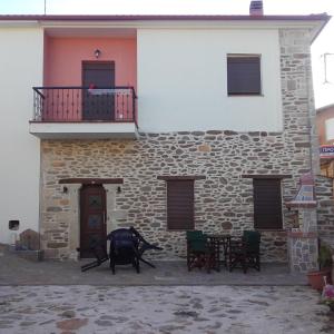 a building with a balcony and a table and chairs at To petrino holidays house in Metangítsion