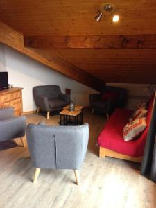 a living room with chairs and a red couch at Les Balcons de Vaujany in Vaujany