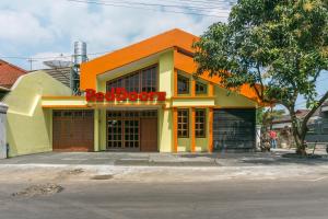 ein orangefarbenes und gelbes Gebäude mit einem roten Schild darauf in der Unterkunft RedDoorz near Universitas Widyagama Malang in Malang