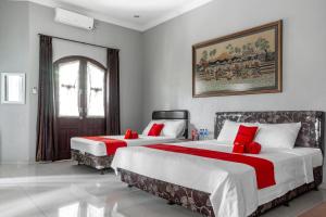 - une chambre avec 2 lits et des oreillers rouges dans l'établissement RedDoorz Syariah near RRI Malang, à Malang