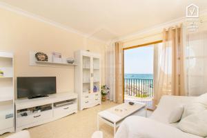 a white living room with a television and a balcony at Apartamentos Carabela CITADINI 39 in Alcudia