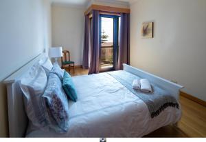 1 dormitorio con cama con almohadas y ventana en Funchal Bay View Holiday Rental, en Funchal