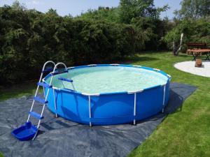 a large blue hot tub with a ladder in a yard at Domek letniskowy Zacisze in Urowo