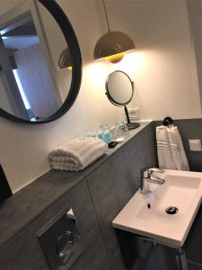 a bathroom with a sink, mirror, and toilet at Fjordgaarden - Kurbad - Hotel - Konference in Ringkøbing