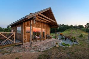 a log cabin with a porch and a patio at Atomiņi in Aucugals