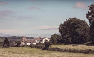 Ein altes Haus auf einem Hügel mit einem Feld in der Unterkunft The New Inn in Carnforth