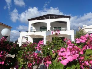a white house with pink flowers in front of it at Villa Magnolia in Coral Bay