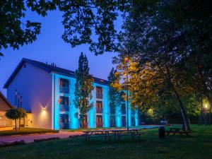 un edificio con bancos delante de él por la noche en Hotel De Schildkamp, en Asperen