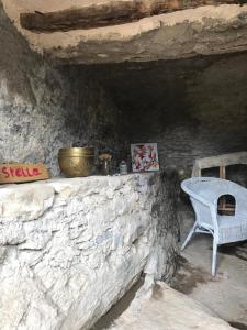 d'un mur en pierre avec une table et une chaise. dans l'établissement ,A cantinella, une cave a fromage au centre corse, à Santa-Lucia-di-Mercurio