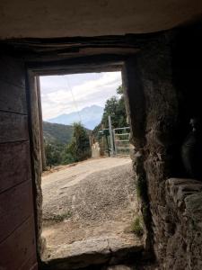 a window in a stone building with a view of a road at ,A cantinella, une cave a fromage au centre corse in Santa-Lucia-di-Mercurio