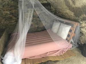 uma cama com uma rede mosquiteira num quarto em ,A cantinella, une cave a fromage au centre corse em Santa-Lucia-di-Mercurio