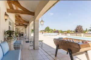 an outdoor patio with a pool and a table with a foos ball at Grande villa d'exception en Normandie tennis, piscine, jacuzzi, salle de fitness in Muids