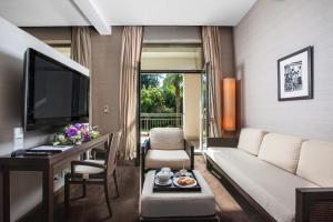 a living room with a couch and a table and a tv at RODINA Grand Hotel & SPA in Sochi