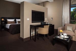 una camera d'albergo con letto e scrivania con TV di RODINA Grand Hotel & SPA a Sochi