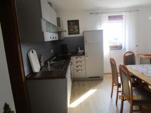 a kitchen with a sink and a refrigerator and a table at Ferienhaus Schöne Aussicht in Esch