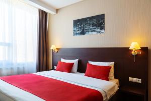 a hotel room with a large bed with red pillows at Gorskiy City Hotel in Novosibirsk