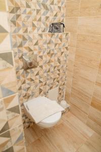 a bathroom with a toilet and a tiled wall at 7 rooms Hotel in Novokuznetsk