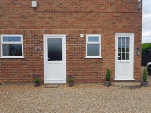 ein Backsteingebäude mit zwei weißen Türen und Topfpflanzen in der Unterkunft The Studio in Ingoldmells