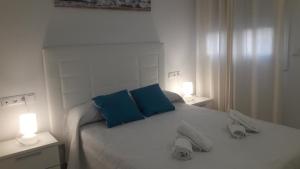 - une chambre blanche avec 2 oreillers bleus sur un lit dans l'établissement APARTAMENTO ICEBERG TARIFA, à Tarifa