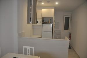 a white kitchen with a refrigerator and a mirror at APARTAMENTO ICEBERG TARIFA in Tarifa
