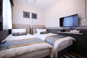 two beds in a room with a flat screen tv at SHINJUKU GLOBAL HOTEL in Tokyo