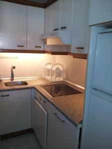 a kitchen with white cabinets and a sink and a counter at Adosado con Piscina y Jardín en Laredo a 100 mtrs de la playa in Laredo