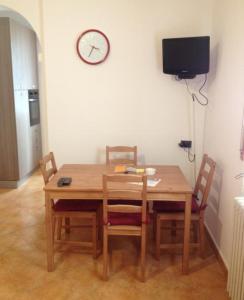a dining room table with chairs and a clock on the wall at Apartment De Rosa in Pero