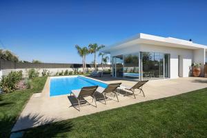 una villa con piscina e sedie in un cortile di Villas Don Serafino a Marina di Ragusa