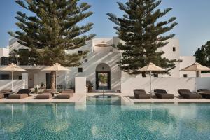 ein Swimmingpool mit Liegestühlen und Sonnenschirmen in der Unterkunft Parilio, a Member of Design Hotels in Naoussa